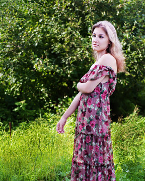 Beautiful girl in floral dress stand in garden.