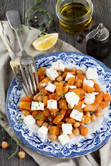 Salad of pumpkin, chickpeas and feta cheese on the old wooden background. 