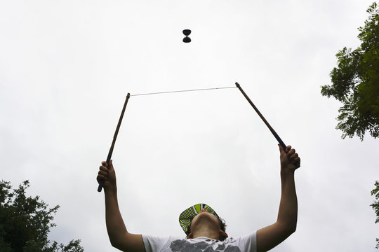 Low angle view of boy playing with diabolo against sky