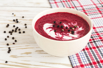 Hot cream beet soup with spices on a wooden background