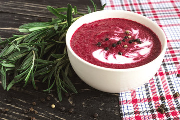 Hot cream beet soup with spices on a wooden background
