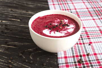 Hot cream beet soup with spices on a wooden background