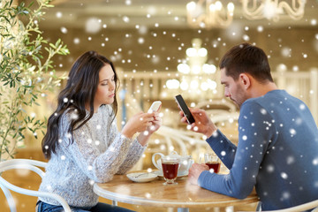 Obraz na płótnie Canvas couple with smartphones drinking tea at cafe