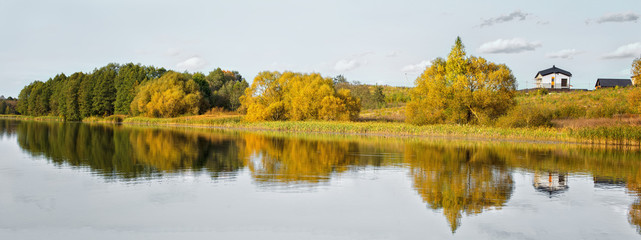 .Autumn landscape with a house on the lake.Panorama.