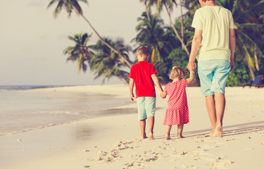 father and two kids walking on summer beach