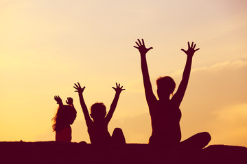 silhouette of happy mother and kids at sunset