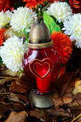 Grave decoration on autumn cemetery. Red snitch and wreath.