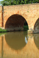 arched bridge made with bricks with the river