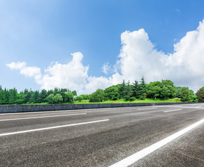 Fototapeta premium asphalt road in front of the green woods