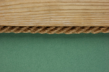 edge of the old wooden planks with rope on the green background