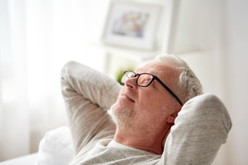 smiling senior man in glasses relaxing on sofa