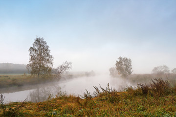Fototapeta na wymiar Autumn foggy morning. Dawn on the misty calm river