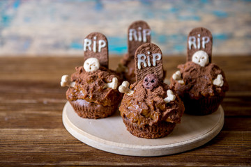 Halloween cupcakes with tombstone cake topper and candle on an old wooden table