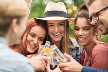 happy friends clinking glasses at summer garden