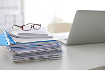 Laptop with stack of folders on table  white background