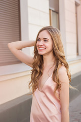 fashion outdoor photo of gorgeous young woman with blond curly hair in elegant clothes posing