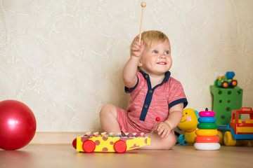 Portrait of a beautiful baby boy on the floor with car toys. 1,5 year-old child playing with educational cup toys at home. Little blond kid with blue eyes is playing with toy at home indoors