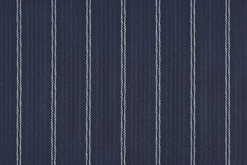 Close up of pinstriped fabric texture background.Detail of navy blue wool suiting with twin white...