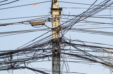 Messy electrical cables and wires on electric pole.