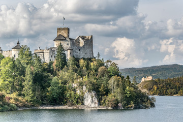Fototapeta na wymiar Castle on the shore of the lake in autumn day with a dramatic sky and white clouds