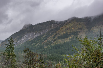 Storm cloud and rain clouds covering the rocky and forest mountains