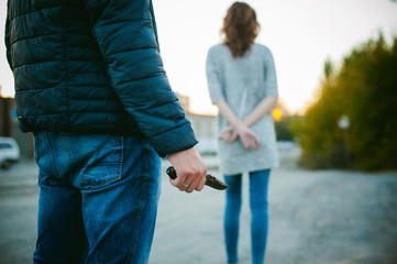 a guy with a knife chasing a girl. Man with a gun in his hand catches up with the young wife of connectedness with hands behind his back.