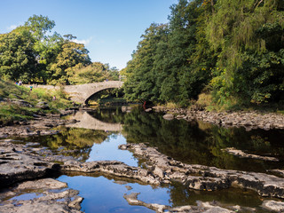 Fototapeta na wymiar The river Ribble at Stainforth bridge in early Autumn sunshine, Stainforth, Settle, North Yorkshire, UK