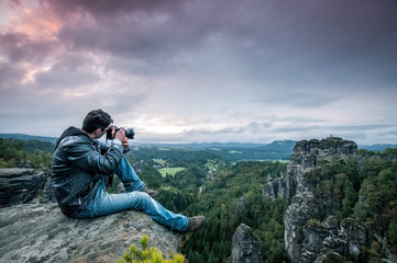 Mann sitzt auf den Berg und macht ein Foto