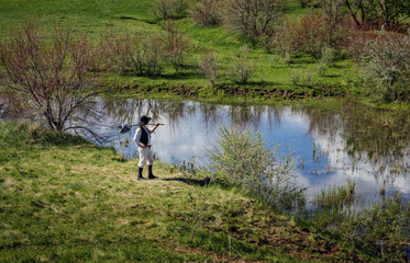 Man in black hat standing on the river bank