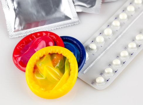 birth control pills and condoms, on white background