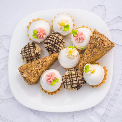 Assorted Fancy Gourmet Cupcakes on a plate. Colorful cupcakes with beautiful decoration over white vintage lace background. 