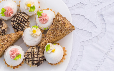 Assorted Fancy Gourmet Cupcakes on a plate. Colorful cupcakes with beautiful decoration over white vintage lace background. 