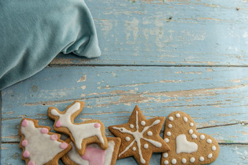 Gingerbread winter cookies with handmade icing with a pillow on a blue table. Heartshaped and starshaped. 