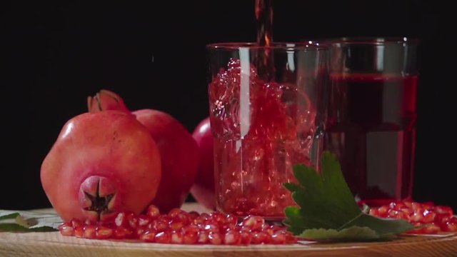 Pouring pomegranate juice into glass slow motion HD video. Still life fruits composition isolated on black background