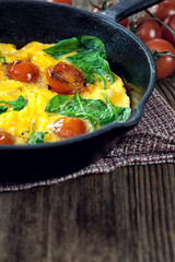 Spinach frittata with cherry tomato in iron skillet 