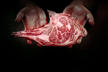 Man hand holding the raw tomahawk beef steak