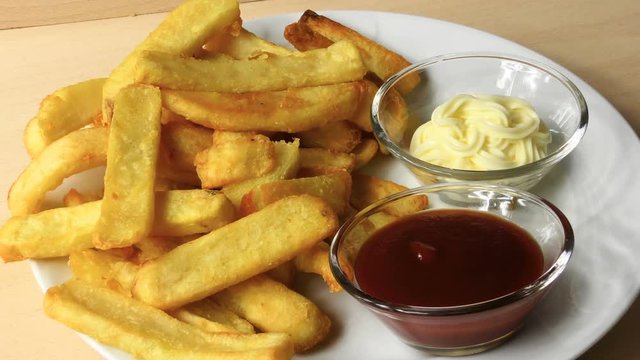French fries with ketchup and mayonnaise. a potato chip is dipped in mayonnaise