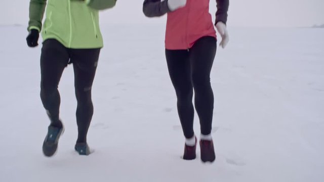 MS Tilt up of determined young couple jogging together in snow