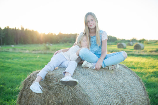 Beautiful young girls sitting on the haystack