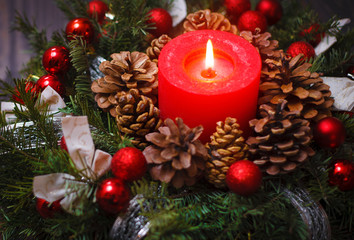 Red candle in a wreath of pine branches with Christmas balls