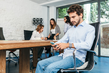 Businessman sitting at the office table with smartphone