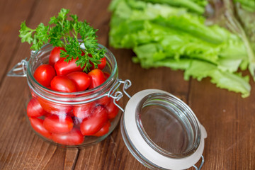 Маленькие помидоры лежат в стеклянной банке