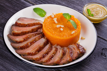 Roast duck breast and pumpkin mash, served with mint and pine nuts. Slices of duck with sweet butter squash, mustard and honey sauce