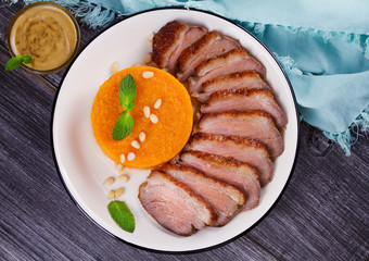 Roast duck breast and pumpkin mash, served with mint and pine nuts. Slices of duck with sweet butter squash, mustard and honey sauce. View From Above, Top Studio Shot