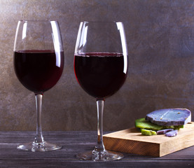 Glasses and bottle red  wine with lavender, pesto cheese and grape on chopping board. Wine and food still life