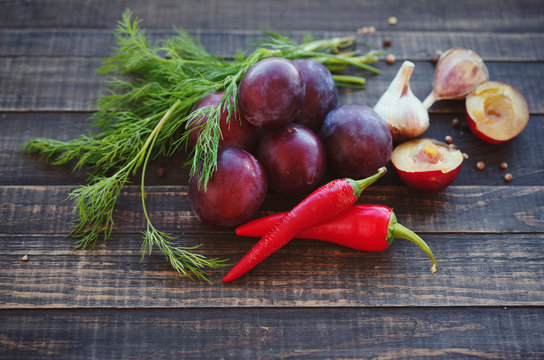 Plums, hot red pepper, garlic, coriander and fennel on rustic wood background. Ingredients for preparation of sauce