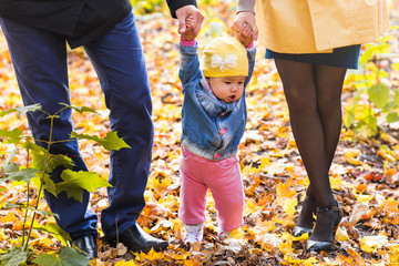 Fototapeta na wymiar happy young family with their daughter spending time outdoor in the autumn park.