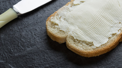 Sandwich, bread with butter and a knife on stone background
