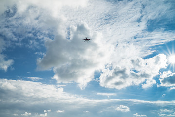 Quadrocopter am Himmel mit Kumuluswolken und Sonne