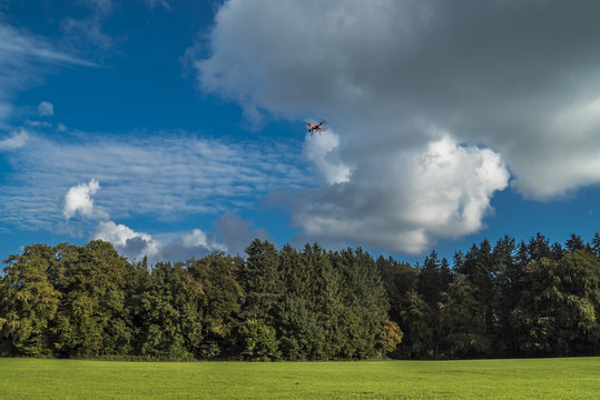 Drohne fliegt entlang des Waldes unter Schäfchenwolken